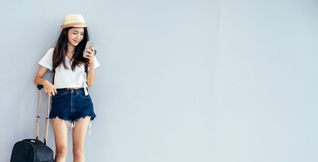 Asian teenage girl is using a smartphone to check flight at the international airport to travel on weekends.の写真素材