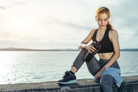 Asian woman is workout and running at the morning, she is warm up her body and drinking water. Healty and sport lifestyle with yoga concept.の写真素材