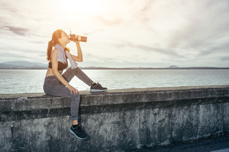 Asian woman is workout and running at the morning, she is warm up her body and drinking water. Healty and sport lifestyle concept.の写真素材