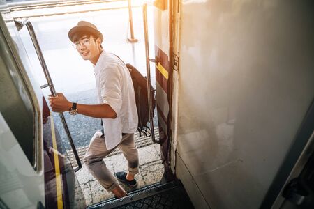 Asian man is traveler, he is waiting for their train. Outdoor adventure travel by train concept. Bangkok, Thailand. Happy/positive/healthy hike/travel/wanderlust conceptの写真素材