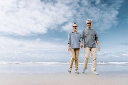 Asian senior couple or elderly people walking and siting at the beach on their weekend vacation holiday. Retirement vaction concept.の写真素材