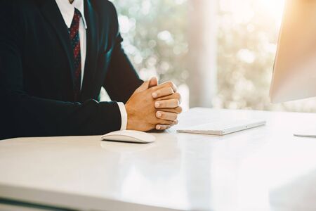 Selective focus to hand of business man in his office holding a pen, typing email and using computer. Business concept.の写真素材