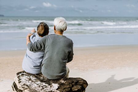 Asian senior couple or elderly people walking and siting at the beach on their weekend vacation holiday. Retirement vaction concept.の写真素材