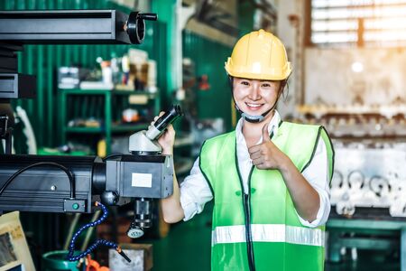 Asian woman is industrial engineer or qc team holding th clipboard while standing in the heavy duty manufacturing shop floor. Factory worker concept.の写真素材