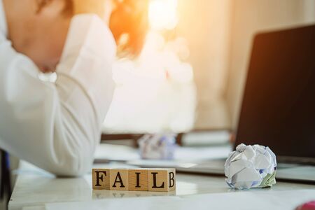 Business man is feeling fail on his business situation, the wooden block with wording fail. Fail business concept.の写真素材