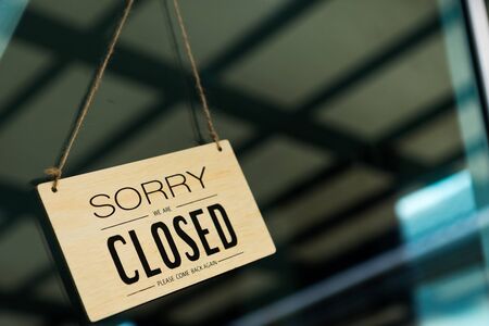 Label 'Sorry we are closed please come back again' notice sign wood board hanging on door front coffee shop.の写真素材