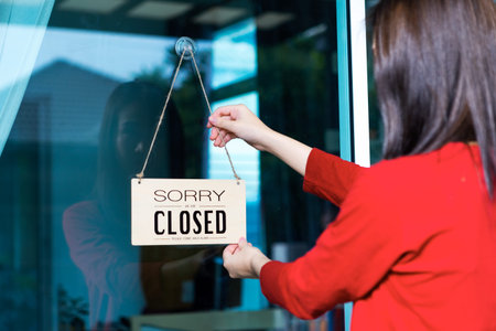 Asian woman shop owner hanging label 'Sorry we are Closed'. She close her shop under pandemic...