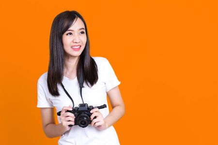 Asian woman smiling pretty girl in white shirt taking photo on camera isolated over color backgroundの写真素材