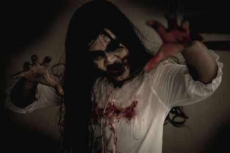 Woman in ghost or zombie on halloween festival at dark place, holding knife and wants to stab you. Horror or halloween festival concept.の写真素材