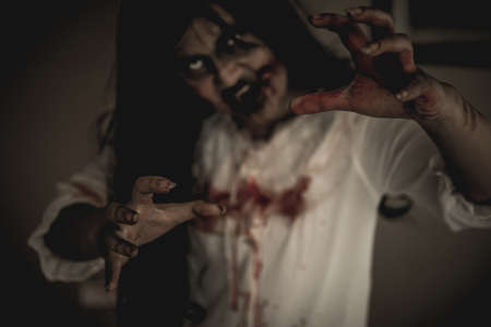 Woman in ghost or zombie on halloween festival at dark place, holding knife and wants to stab you. Horror or halloween festival concept.の写真素材