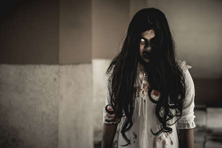 Woman in ghost or zombie on halloween festival at dark place, holding knife and wants to stab you. Horror or halloween festival concept.の写真素材