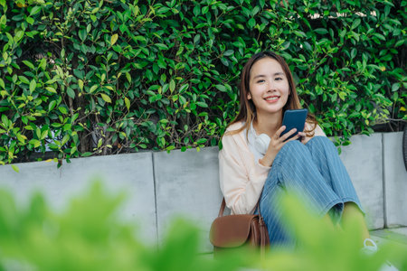 Beautiful Asian woman listening favourite music on headphones from mobile phone, Happiness relaxation summer in park with music riding bicycle in green park.の写真素材