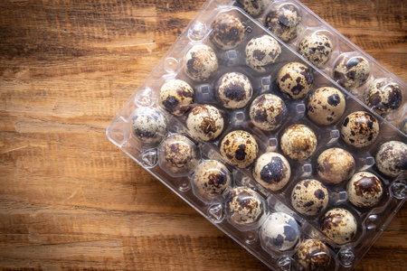 Quail eggs in  packaging on wooden background and space for text