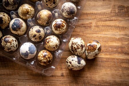 Quail eggs in plastic container on wooden background from supermarketの写真素材