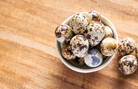 Fresh quail egg in bowl on a wooden background with space for textの写真素材