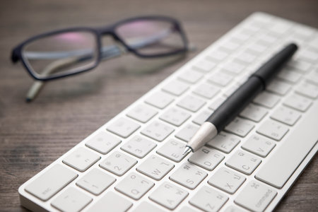 Close-up fountain pen on the keyboard with glasses
