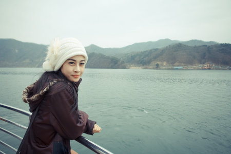 Woman wearing a jacket, standing by the river.の写真素材