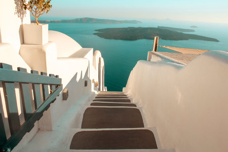 Close up, white and black stairs to the sea with a little island in the background. Location: Santorini, the white townの写真素材