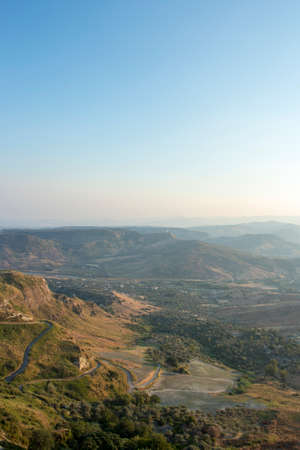 aerial view of Gerace, Calabria (Italy) at the sunset. A south italian village. Panoramic view of Gerace from below at the sunset, it is possible to see the stone houses and the wood around them. The vilの写真素材