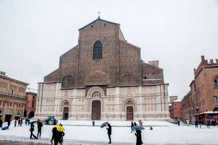 view of Maggiore square ( piazza maggiore ) or basilica di San Petronio ( San Petronio cathedral) in Bologna covered to snow in last winter, with person and umbrella.のeditorial素材