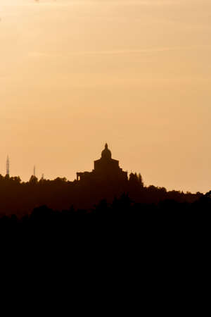 Panoramic view of San Luca Sanctuary at the sunset, with orange sky and sun in the background. There is the wood of the Bologna's hills ( colli bolognesi). Emilia Romagna Region.の写真素材
