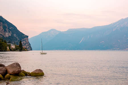 Lago di Garda ( Garda lake ) at sunset with light pink - a mountain in background. Long exposure time - little wavesの写真素材