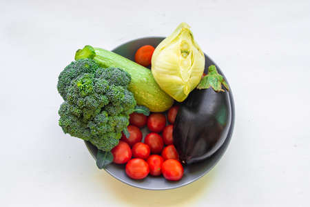 Healthy food clean eating selection: fruit, vegetable, superfood, avocado, papaya leaf vegetable in a dish on white concrete backgroundの写真素材