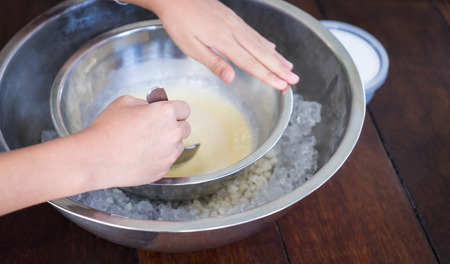 Children hand making home made ice cream with iced bowl. Spinning steel bowl for making Vanilla Ice Cream.の写真素材