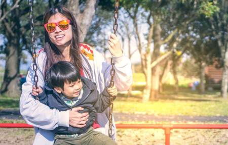 Mother Holding her child on a Swing playground with copy space, vitntage toneの写真素材