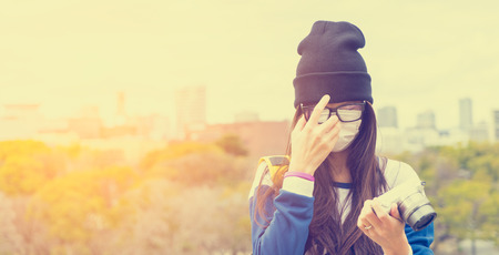 Asian girl with hat and glasses are checking on her cameraの写真素材