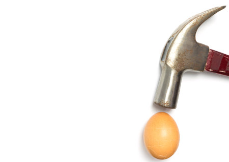 Hammer hitting a cracked egg isolated on white with copy space.