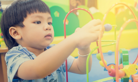 Asian children playing on educational toy. Japanese baby learning to count with colorful toy. Number learning practice in kindergarten class room for children.の写真素材