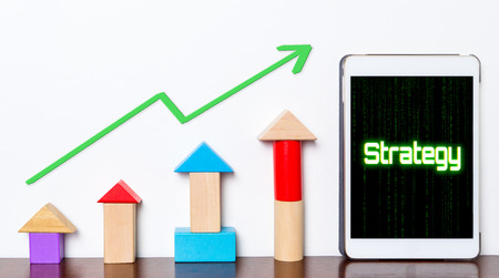 Strategy Business success growing concept on tablet. Toy block rise with Strategy planning stepping up diagram graph. Tablet with hi tech tech text Business strategy success rising up.の写真素材