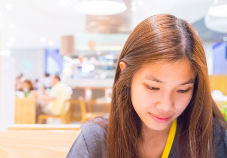 Japanese girl portrait in a Cafe using smart phone.の写真素材