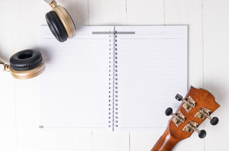 Headphone and guitar on a blank book page for song writing. Music instrument notes.の写真素材