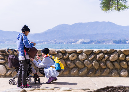 Miyajima, Japan - March 16, 2016: A Family with small child traveling in Miyajima beach.のeditorial素材