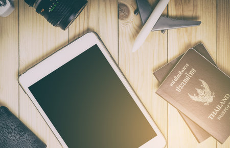 Blank tablet screen with travel equipments. Travel items and tablet on wooden table in vintage tone....