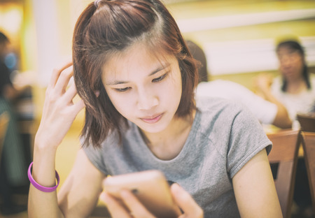 Cute short hair asian girl using a mobile phone in cafe.の写真素材