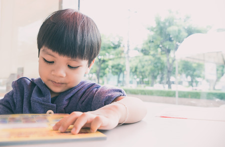 Asian 3 year old boy is reading picture book with copy space.の写真素材