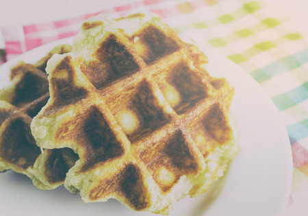 Baked golden honey waffles on white plate in vintage tone.の写真素材