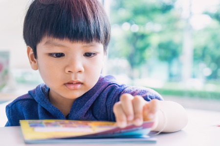 Japanese boy is reading a educational play book.の写真素材