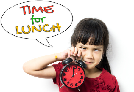 Asian little kid is holding the clock reminding you she need to go for lunch.の写真素材