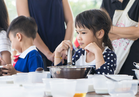 Asian children enjoying educational cooking class. They making homemade ice cream with family. Homemade baking and cooking with family help child develop skills. Children learning to use baking tool.の写真素材
