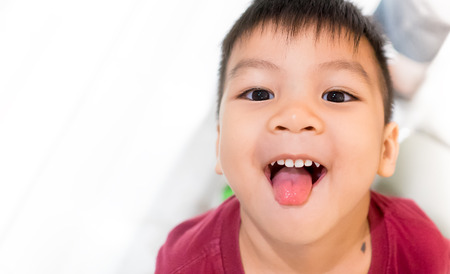 Asian boy is sticking his tongue out smiling.の写真素材
