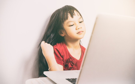 Long hair Asian girl is looking beautiful using Video call on Internet. She is too your to use social network and Internet can be dangerous to small child.の写真素材