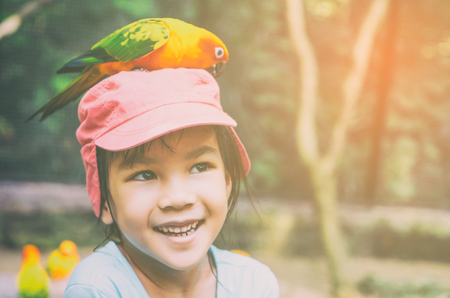 Parrot is eating food on little girl head.の写真素材