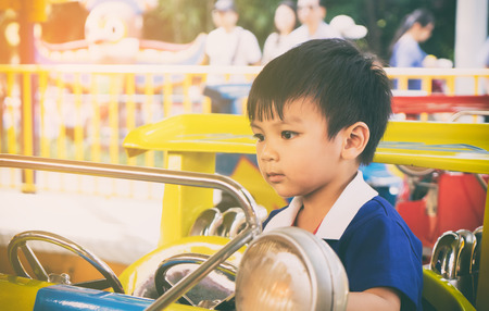 Asian boy is riding on a toy car ride.の写真素材