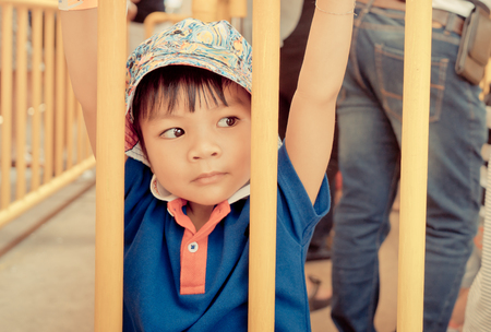 Little Asian boy hanging on a metal fence.の写真素材