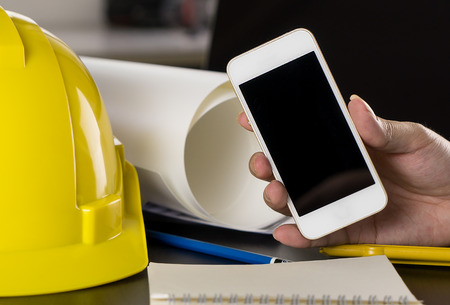 Construction worker holding blank phone for copy space.の写真素材