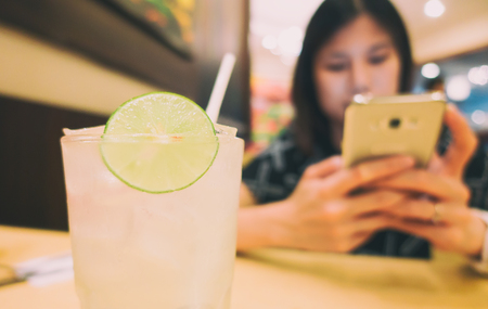 Glass of lemonade in cafe with asian girlの写真素材